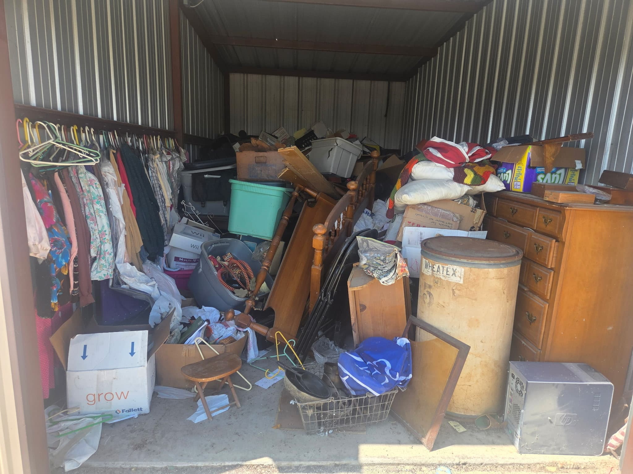 Royse City storage unit packed with furniture, boxes and racks of clothes before the cleanout